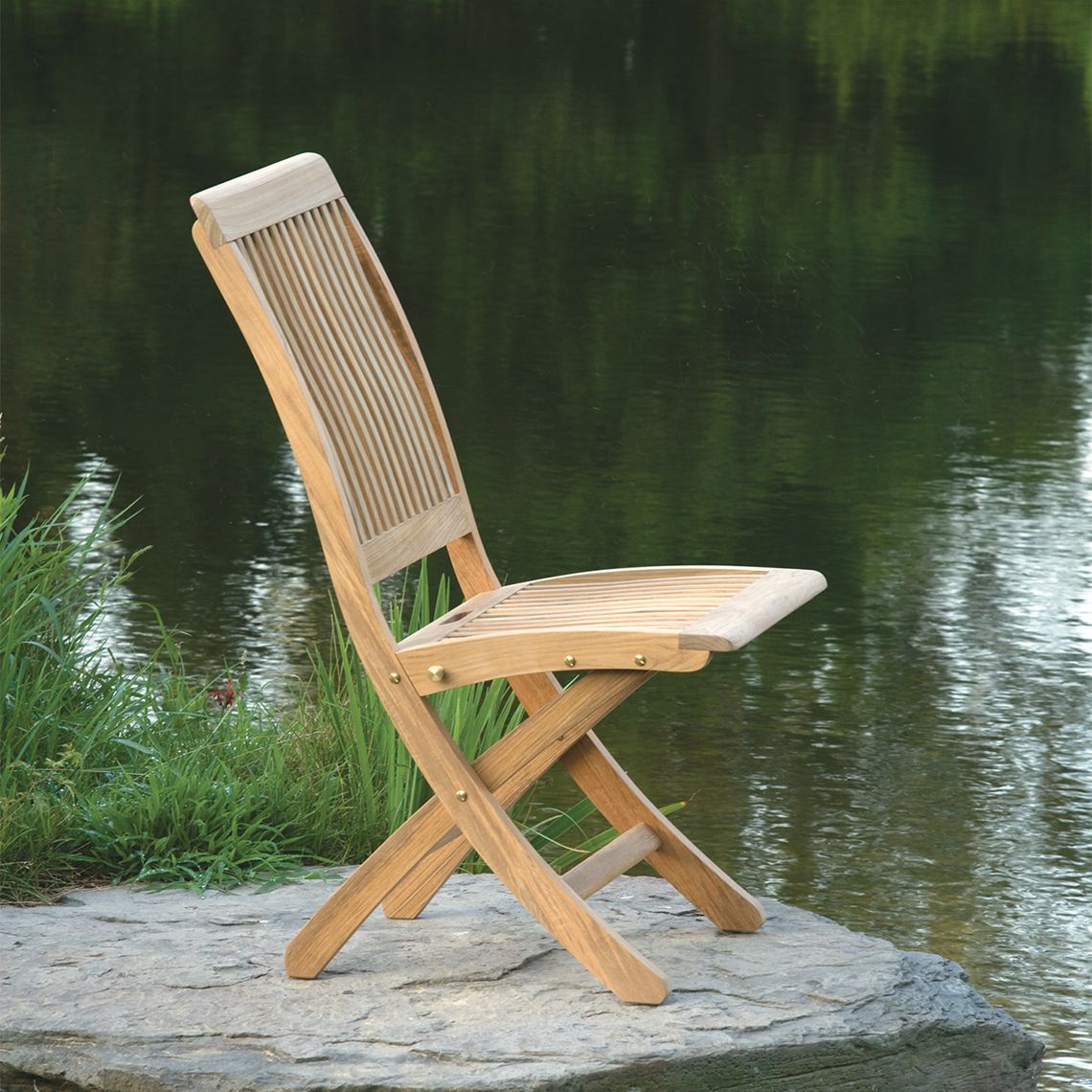 The Monterey dining side chair combines graceful curves with practical functionality. Crafted from solid Grade A teak, it withstands diverse climates including salt air, rain, and snow. The folding design with locking mechanism offers convenient storage. - alternate view